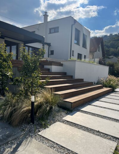 Realizácia okrasnej záhrady s drevenou terasou, osvetlením a veľkoformátovou dlažbou z betónu v Hainburg – realizácia Creanatura